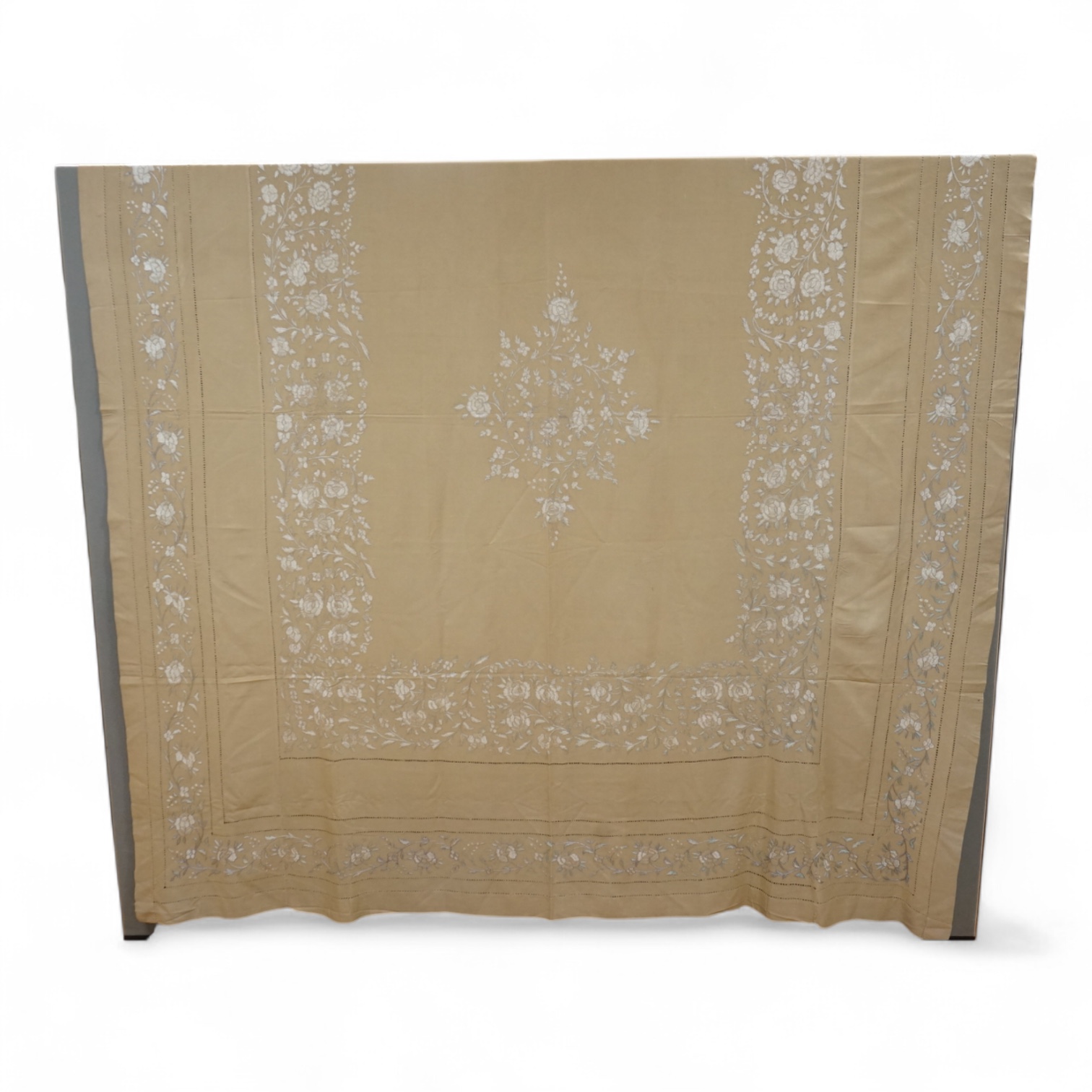 A 1920’s heavy shantung silk hand embroidered table cover. Worked with decorative rows of button hole stitch. Embroidered with white, green and blue silk flowers. 240cm x 204cm. Condition - some fine holes near corners,